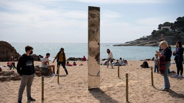 Pessoas em torno de monólito de metal que surgiu na praia de Sa Conca, em Castell-Platja D'Aro, Espanha, 31 de março de 2021 - Sputnik Brasil