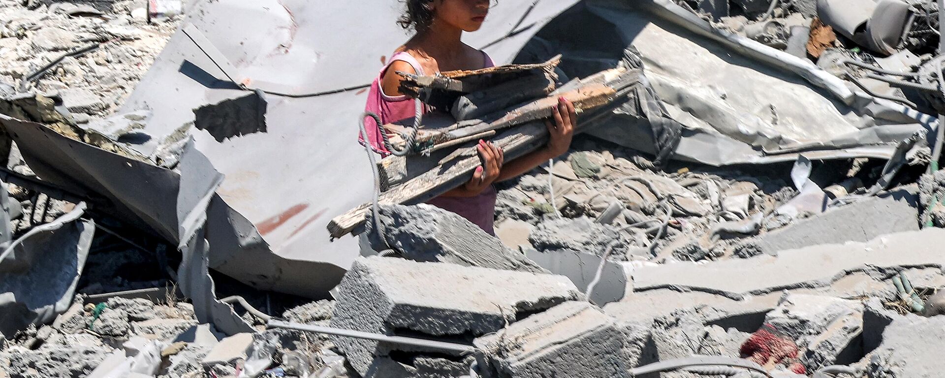 Uma menina caminha com madeira recuperada entre os escombros no local de um prédio que foi atingido por bombardeios israelenses no bairro de Sabra, no sul da Cidade de Gaza, em 27 de junho de 2024 - Sputnik Brasil, 1920, 29.06.2024
