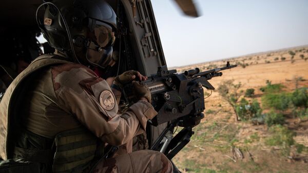 Um soldado da força Barkhane segura uma arma em um helicóptero enquanto voa perto da base militar de Ouallam durante uma visita oficial dos Ministros dos Relações Exteriores e das Forças Armadas franceses ao Níger, em 15 de julho de 2022 - Sputnik Brasil