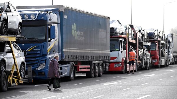 Mulher passa por caminhões, que formam fila para cruzar a fronteira entre a Polônia e a Ucrânia no cruzamento de Medyka, no sudeste da Polônia, 30 de março de 2024 - Sputnik Brasil