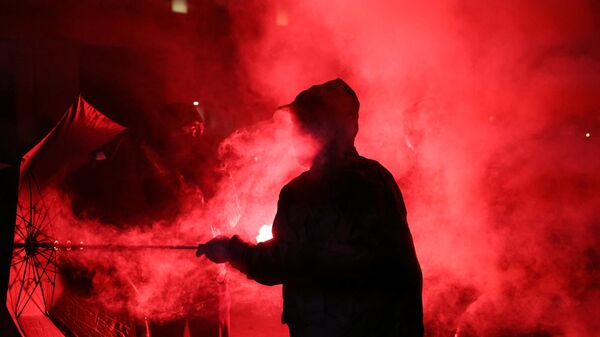 Um manifestante segura um guarda-chuva em uma nuvem de fumaça durante uma reunião na noite após os resultados do segundo turno das eleições legislativas da França na Praça da República, Paris, 8 de julho de 2024 - Sputnik Brasil
