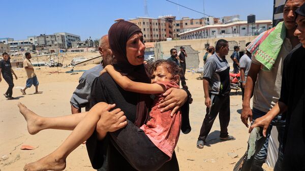 Uma mulher palestina carrega uma criança ferida para o hospital Nasser em Khan Yunis em 13 de julho de 2024, um dos estabelecimentos de saúde para onde as vítimas foram levadas às pressas depois que um ataque israelense matou pelo menos 71 pessoas e feriu muitas outras no campo de Al-Mawasi - Sputnik Brasil