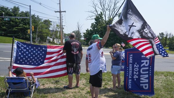 Apoiadores do ex-presidente Donald Trump seguram bandeiras dos EUA e cartazes da campanha para a presidência perto do Trump National Golf Club. Nova Jersey, 14 de julho de 2024. - Sputnik Brasil
