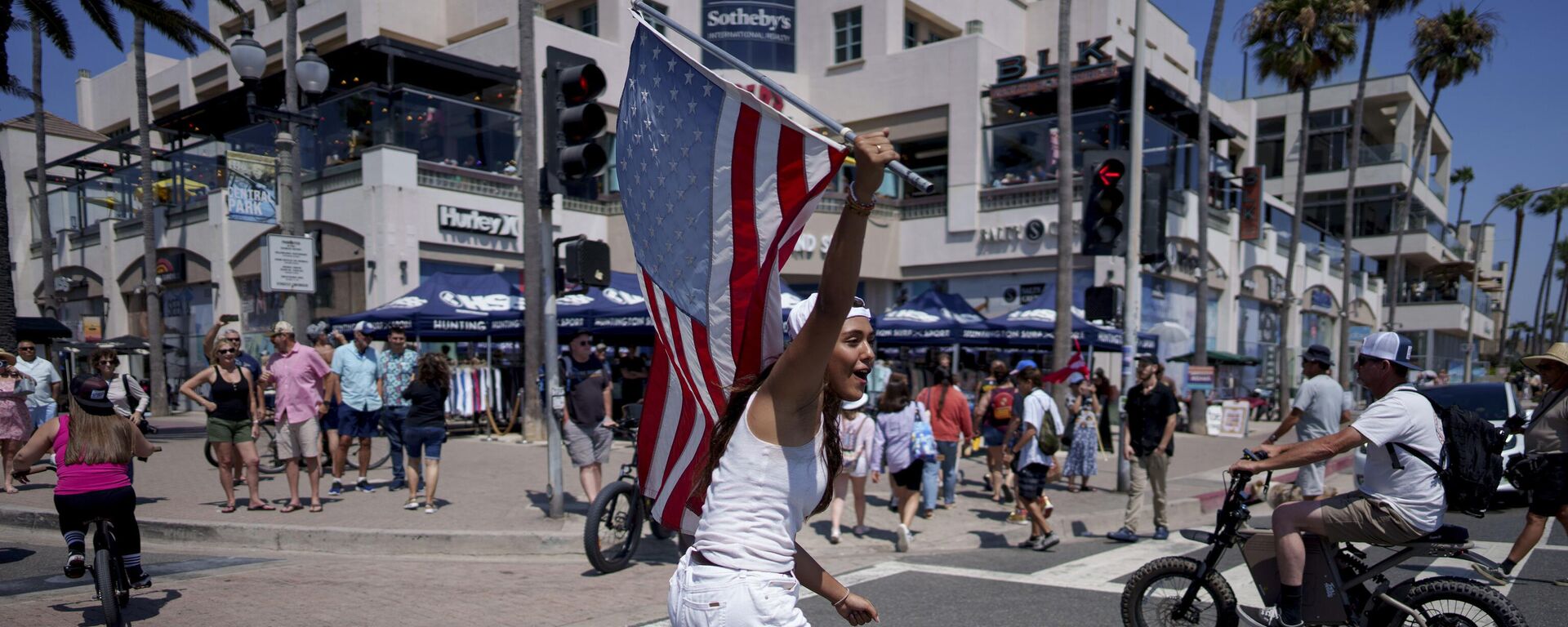 Uma mulher anda de skate em um comício de apoio ao candidato presidencial republicano, ex-presidente Donald Trump, em Huntington Beach, Califórnia, 14 de julho de 2024 - Sputnik Brasil, 1920, 15.07.2024