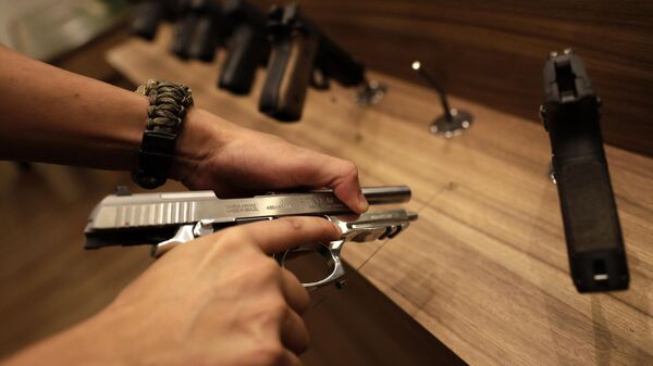 Um vendedor demonstra uma arma dentro da loja de armas Big Boar, em Brasília (DF), em 4 de março de 2021 - Sputnik Brasil