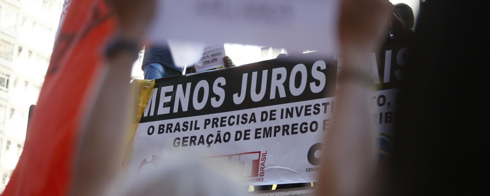 Cartaz segurado em frente ao Banco Central por manifestantes em ato das centrais sindicais pede redução da taxa de juros no Brasil. São Paulo, 18 de junho de 2024 - Sputnik Brasil, 1920, 17.07.2024