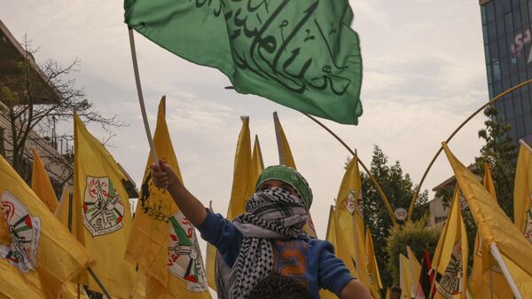 Uma criança agita a bandeira do Hamas enquanto outras agitam o emblema do Fatah, durante uma marcha de solidariedade com os palestinos da Faixa de Gaza, na cidade ocupada de Hebron, na Cisjordânia, em meio às batalhas contínuas entre Israel e o movimento palestino Hamas, em 27 de outubro de 2023 - Sputnik Brasil