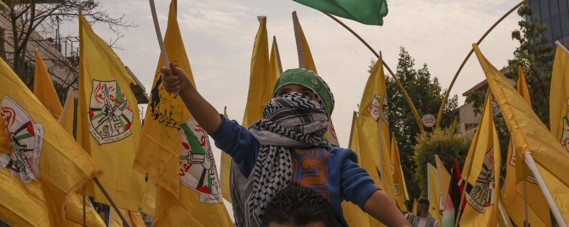 Uma criança agita a bandeira do Hamas enquanto outras agitam o emblema do Fatah, durante uma marcha de solidariedade com os palestinos da Faixa de Gaza, na cidade ocupada de Hebron, na Cisjordânia, em meio às batalhas contínuas entre Israel e o movimento palestino Hamas, em 27 de outubro de 2023 - Sputnik Brasil, 1920, 20.07.2024