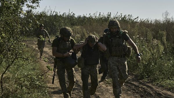 Militares ucranianos ajudam a evacuar um soldado ferido na linha de frente perto de Bakhmut, região de Donetsk, 30 de agosto de 2023 - Sputnik Brasil