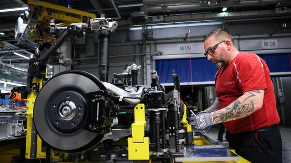 Um funcionário da montadora alemã Porsche AG trabalha na bateria e no chassi de um novo modelo Porsche Macan 4 Electric na linha de montagem da unidade de produção da montadora alemã em Leipzig, leste da Alemanha, 6 de maio de 2024 - Sputnik Brasil