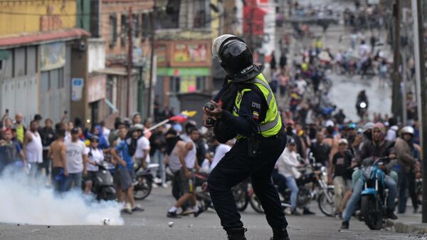 Um policial da tropa de choque usa gás lacrimogêneo contra manifestantes durante um protesto de oponentes do governo do presidente venezuelano Nicolás Maduro no bairro de Catia, em Caracas, 29 de julho de 2024 - Sputnik Brasil