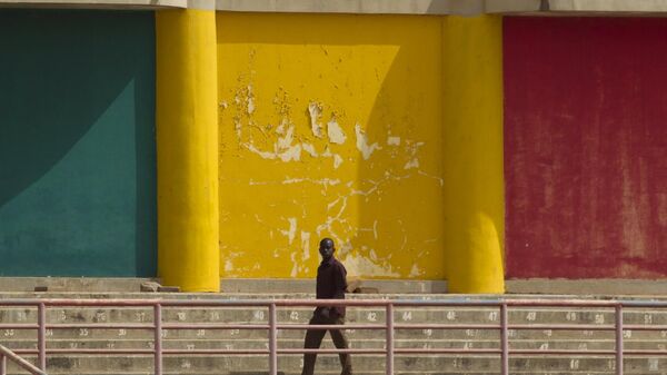 Um homem caminha em frente a um muro pintado com as cores da bandeira do Mali (foto de arquivo) - Sputnik Brasil