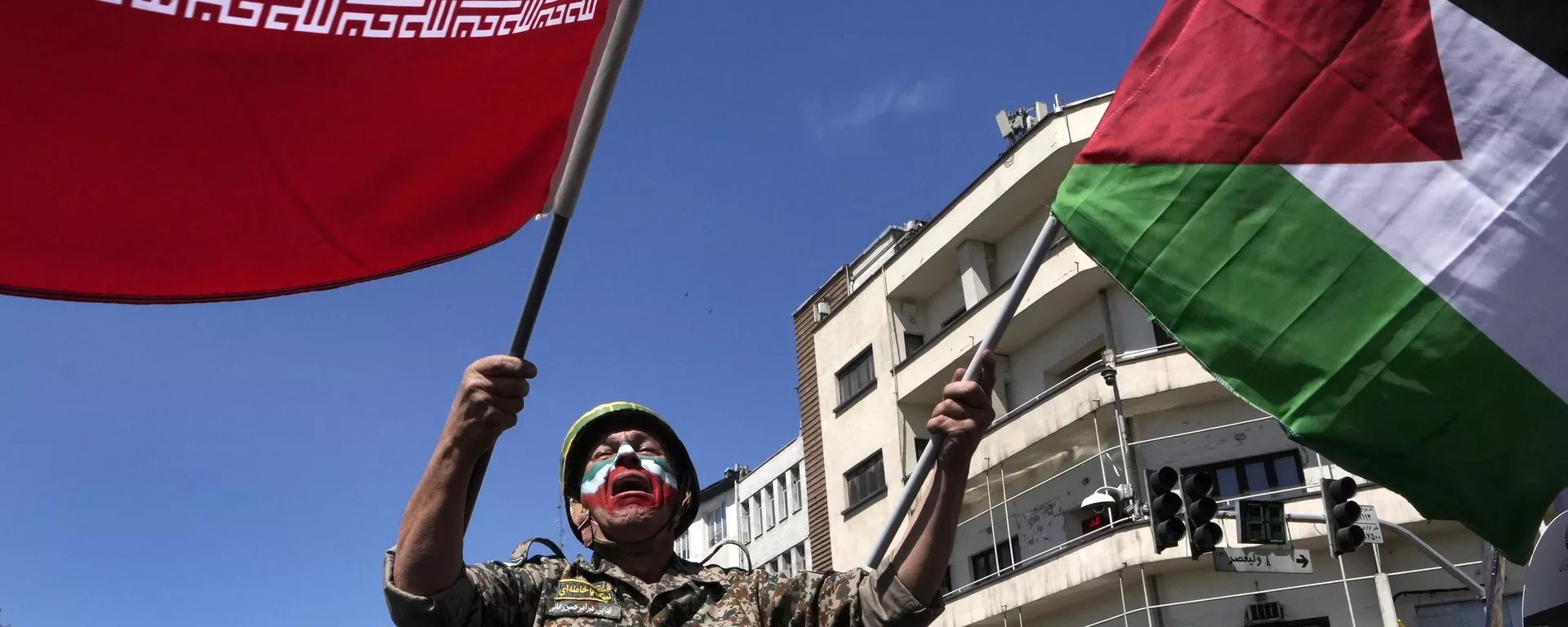 Com o rosto pintado nas cores da bandeira iraniana, um homem chora enquanto agita bandeiras iranianas e palestinas no comício anual para marcar o Dia de Quds, ou Dia de Jerusalém, em apoio aos palestinos, em Teerã, Irã, 5 de abril de 2024 - Sputnik Brasil, 1920, 11.05.2025