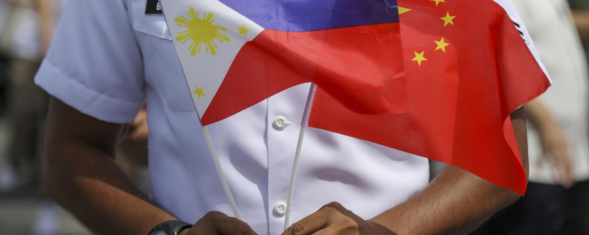 Membro da Guarda Costeira filipina segura bandeiras das Filipinas e da China durante chegada de navio de treinamento naval chinês Qi Jiguang, que participa de visita de boa vontade no porto de Manila. Filipinas, 14 de junho de 2023 - Sputnik Brasil, 1920, 14.11.2024