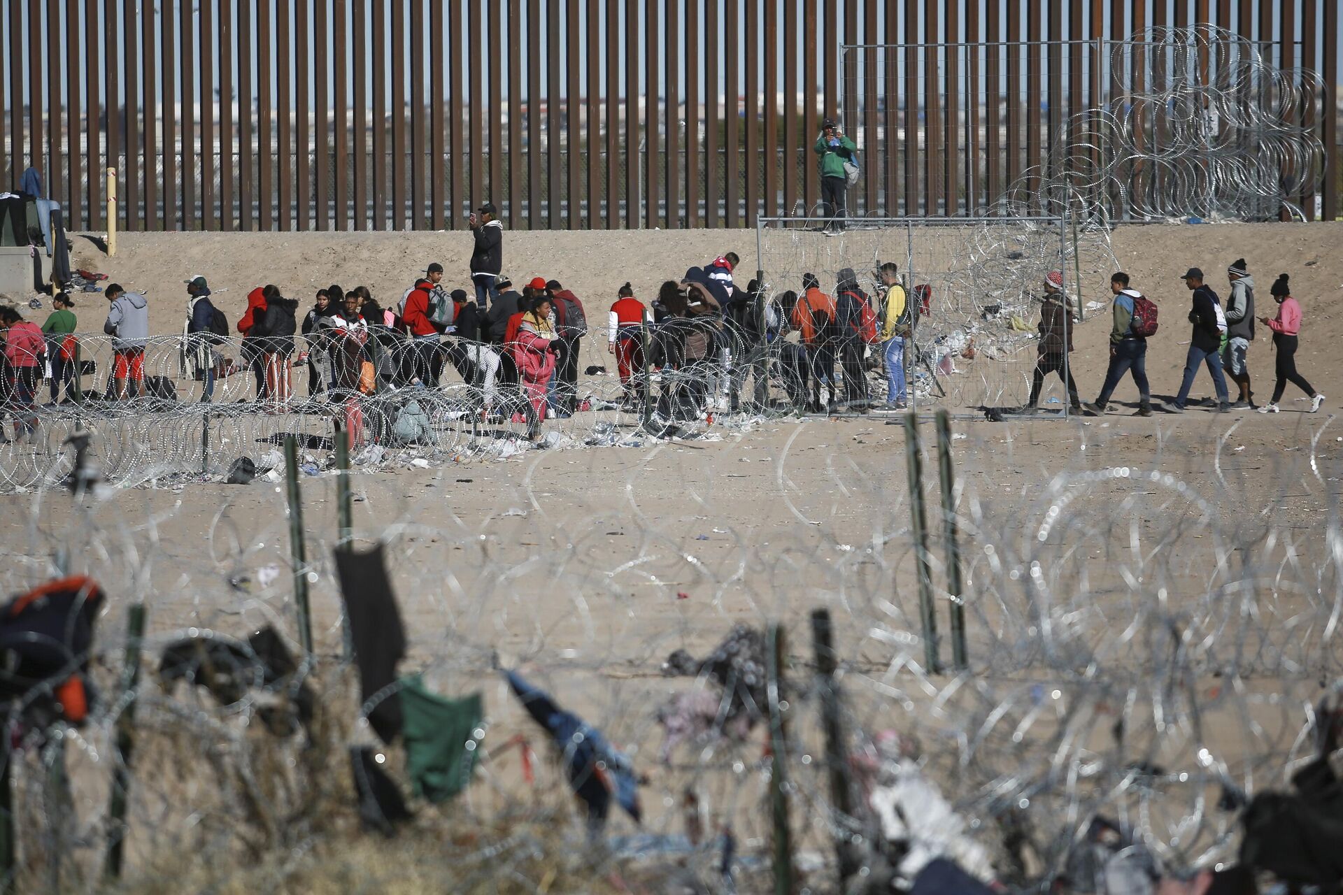 Migrantes fazem fila no muro da fronteira dos EUA com México após serem detidos pelas autoridades de imigração norte-americanas, visto de Ciudad Juarez, México, 27 de dezembro de 2023