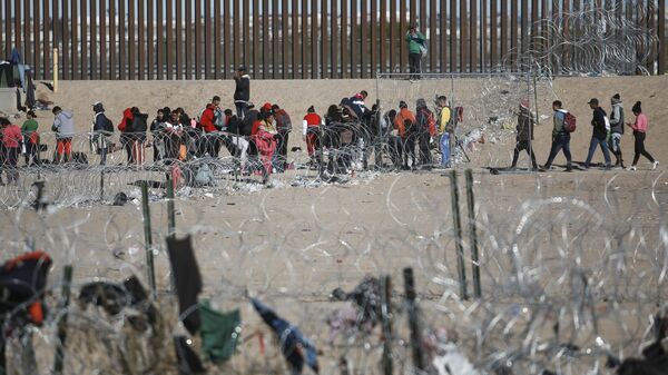 Migrantes fazem fila no muro da fronteira dos EUA com México após serem detidos pelas autoridades de imigração norte-americanas, visto de Ciudad Juarez, México, 27 de dezembro de 2023 - Sputnik Brasil