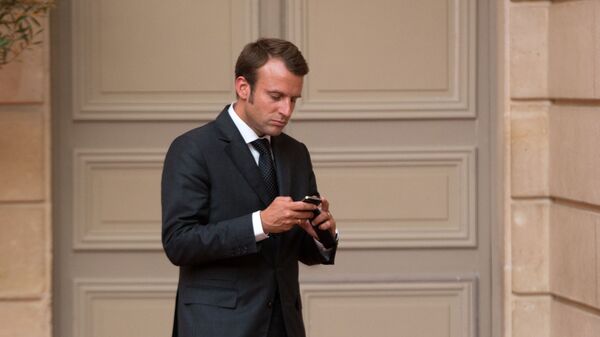 O então ministro da Economia francês, Emmanuel Macron, olha para seu telefone ao chegar a um jantar com a presença do presidente francês François Hollande e do ministro da Defesa e príncipe herdeiro saudita Salman bin Abdul-Aziz no Palácio do Eliseu em Paris, 1º de setembro de 2014 - Sputnik Brasil