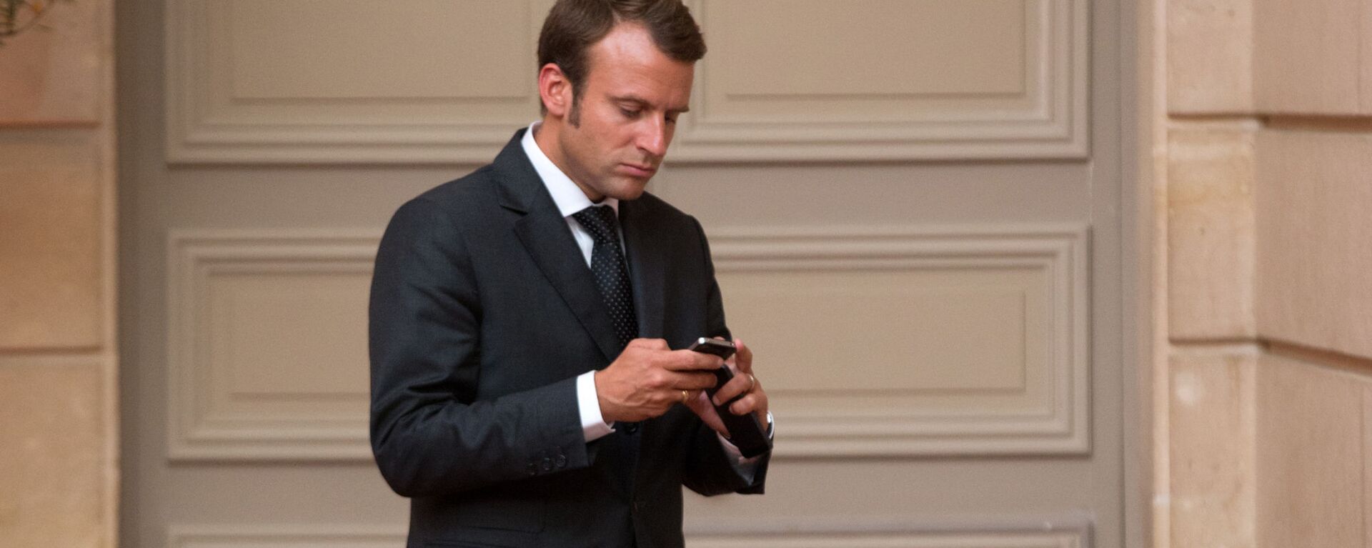 O então ministro da Economia francês, Emmanuel Macron, olha para seu telefone ao chegar a um jantar com a presença do presidente francês François Hollande e do ministro da Defesa e príncipe herdeiro saudita Salman bin Abdul-Aziz no Palácio do Eliseu em Paris, 1º de setembro de 2014 - Sputnik Brasil, 1920, 30.08.2024