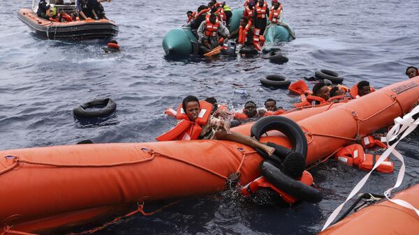 Migrantes a bordo de um bote inflável acabam na água antes de serem resgatados, a cerca de 35 milhas da Líbia. Outubro de 2021 - Sputnik Brasil