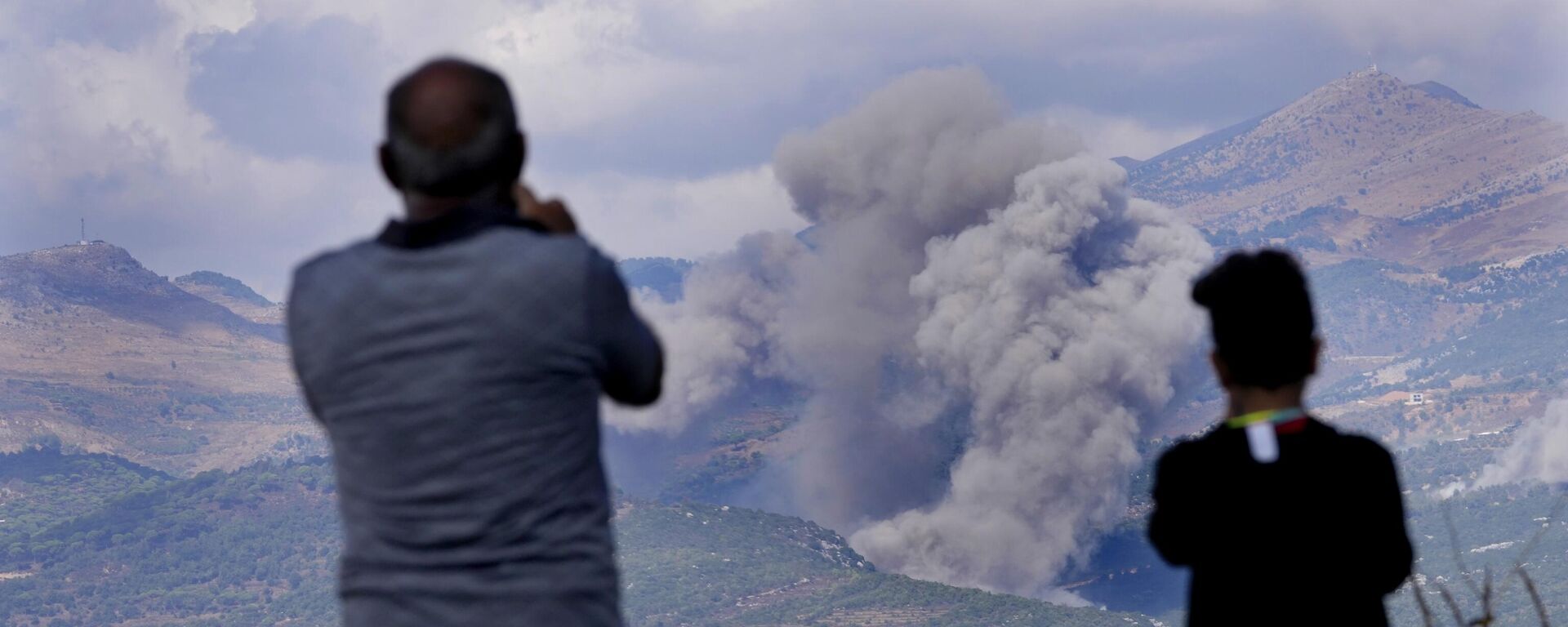 Cidadãos libaneses observam a fumaça dos ataques aéreos israelenses nas montanhas Mahmoudiyeh, vista da cidade de Marjayoun, sul do Líbano, 21 de setembro de 2024 - Sputnik Brasil, 1920, 21.09.2024