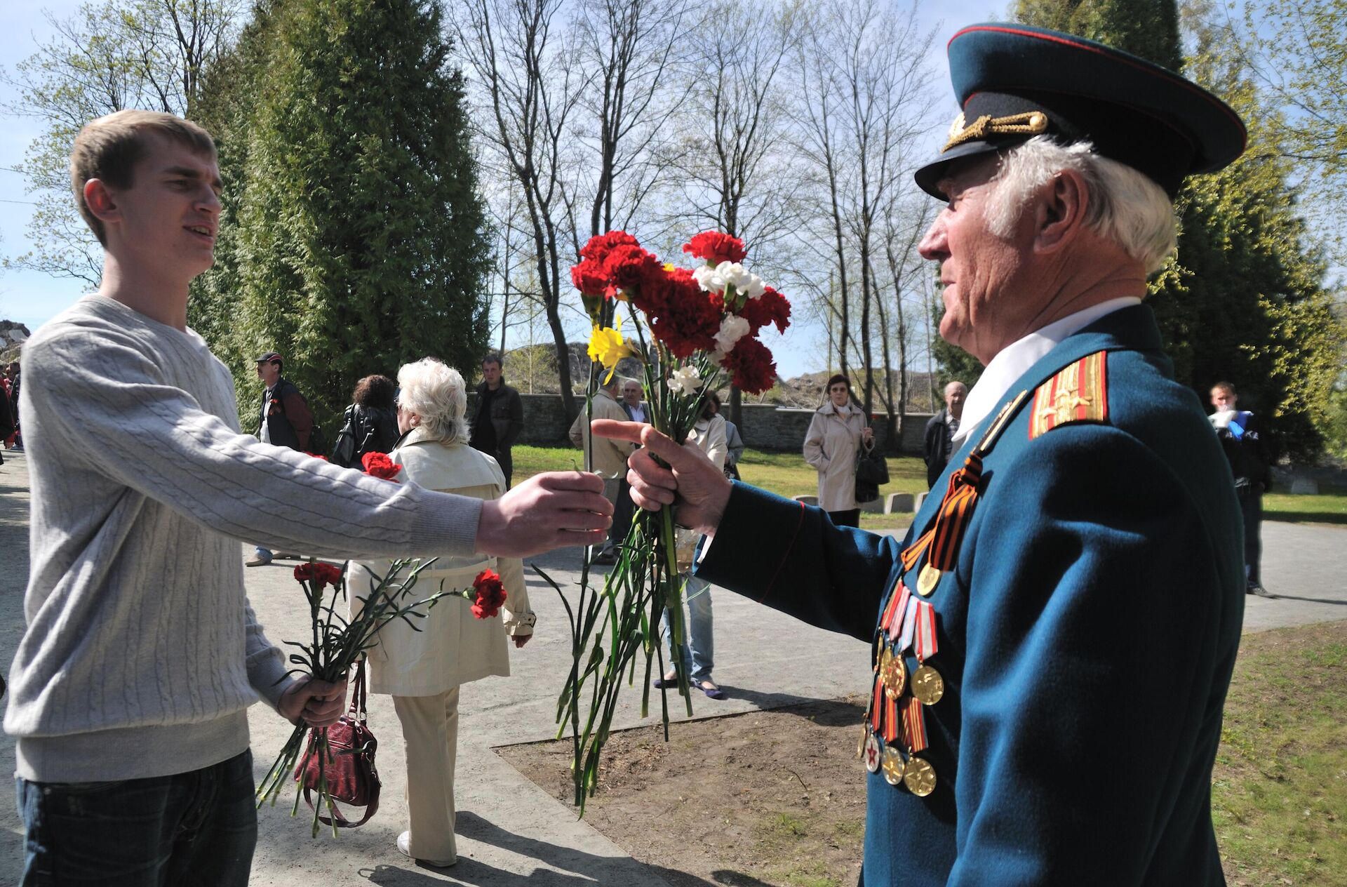 Um jovem entrega flores a um veterano da Grande Guerra Patriótica em 9 de maio no monumento ao Soldado Libertador (também conhecido como Soldado de Bronze), localizado em um cemitério militar em Tallinn, Estônia - Sputnik Brasil, 1920, 22.09.2024