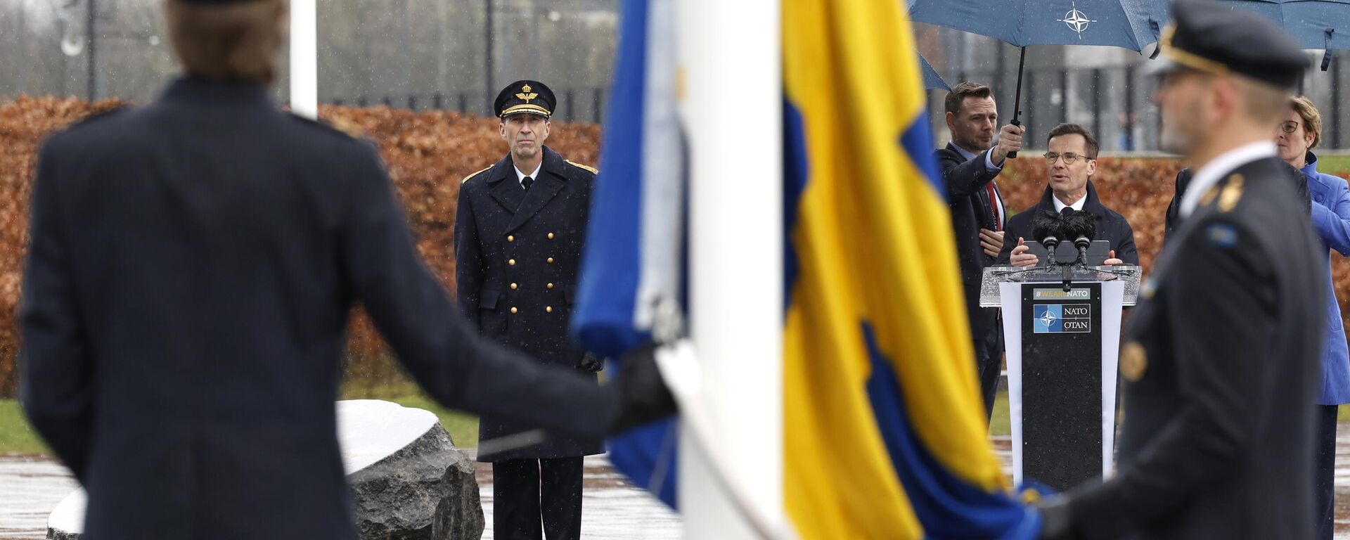 O primeiro-ministro da Suécia, Ulf Kristersson, de centro-direita, fala enquanto militares se preparam para hastear a bandeira da Suécia durante uma cerimônia para marcar a adesão da Suécia à OTAN na sede da OTAN em Bruxelas - Sputnik Brasil, 1920, 07.10.2024