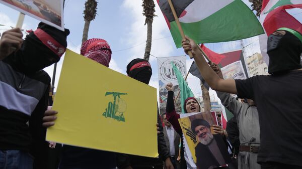 Ativistas palestinos gritam slogans enquanto seguram cartazes com fotos do falecido líder do Hezbollah, Hassan Nasrallah, e bandeiras do Hezbollah, Líbano e Palestina durante um protesto para marcar o aniversário de um ano da guerra entre Israel e Hamas, na cidade de Ramallah. Cisjordânia, 7 de outubro de 2024 - Sputnik Brasil