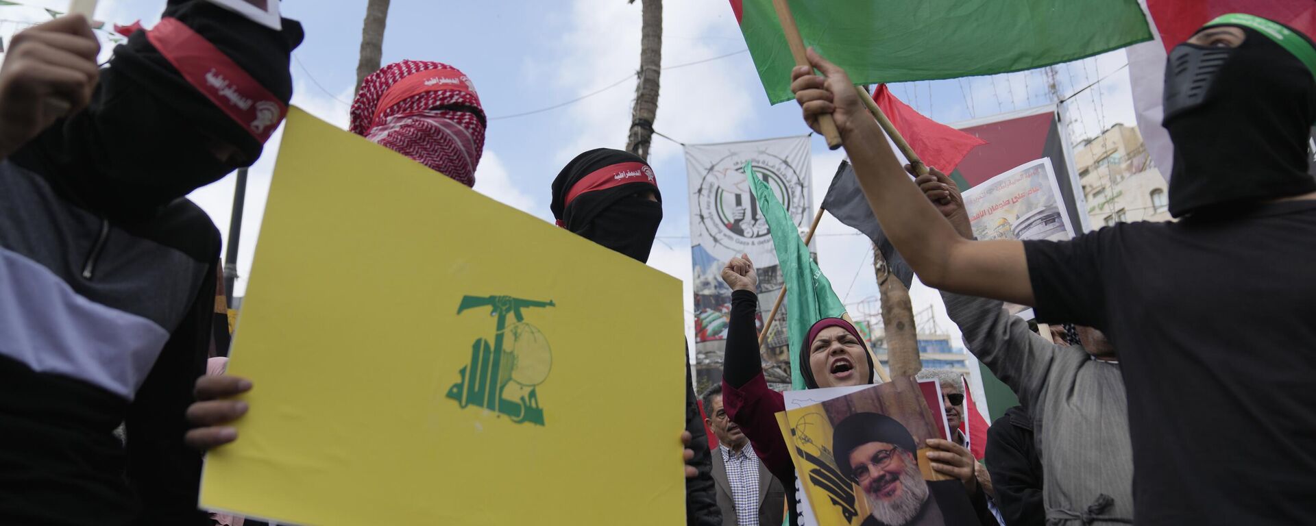 Ativistas palestinos gritam slogans enquanto seguram cartazes com fotos do falecido líder do Hezbollah, Hassan Nasrallah, e bandeiras do Hezbollah, Líbano e Palestina durante um protesto para marcar o aniversário de um ano da guerra entre Israel e Hamas, na cidade de Ramallah. Cisjordânia, 7 de outubro de 2024 - Sputnik Brasil, 1920, 22.10.2024