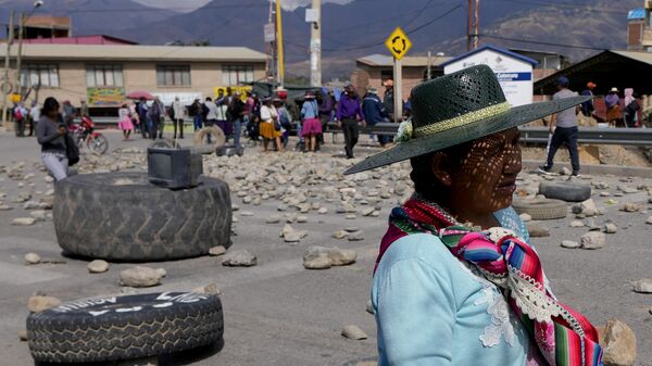 Mulher passa por uma barricada montada por apoiadores do ex-presidente boliviano Evo Morales, que estão bloqueando estradas para impedi-lo de enfrentar uma investigação criminal por um suposto abuso de menor. Cochabamba, Bolívia, novembro de 2024 - Sputnik Brasil