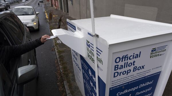 Uma pessoa deixa sua cédula eleitoral de 2024 em uma caixa de coleta recém-instalada do lado de fora do escritório da Divisão Eleitoral do Condado de Multnomah, em Portland, Oregon, 28 de outubro de 2024 - Sputnik Brasil