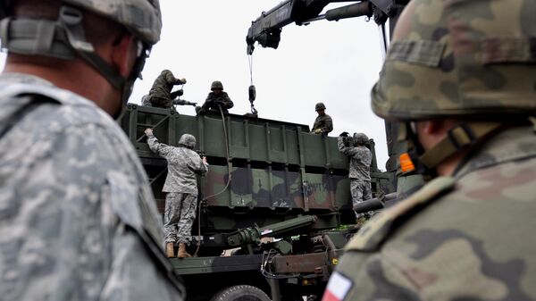 Soldados da Bateria Alfa do Exército dos EUA na Europa, 5º Batalhão, 7º Regimento de Artilharia de Defesa Aérea, familiarizam os militares poloneses sobre como carregar/descarregar recipientes de mísseis Patriot em Morag, Polônia, 8 de junho de 2010 - Sputnik Brasil