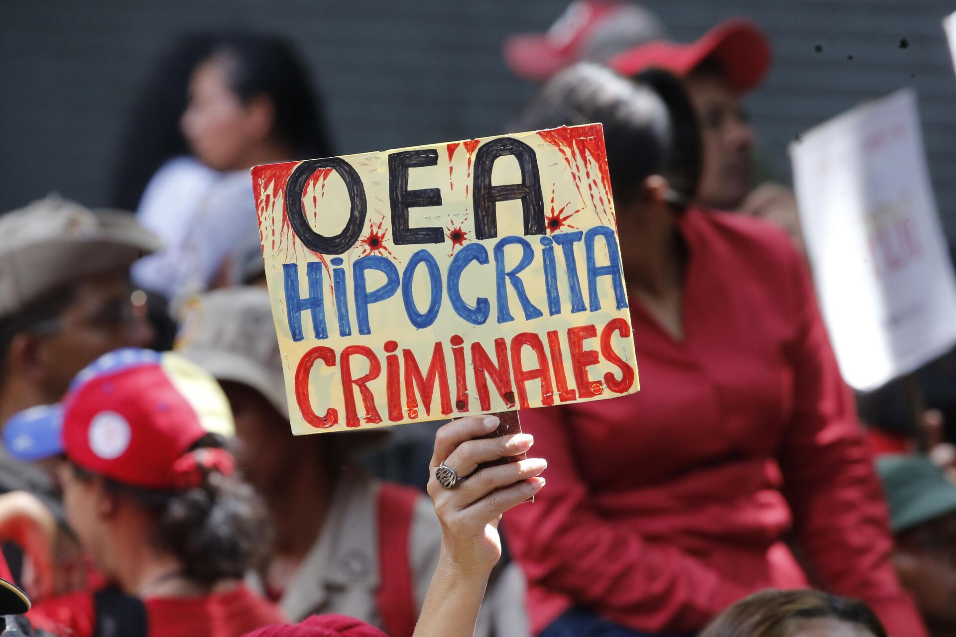 Manifestante favorável ao presidente da Venezuela, Nicolas Maduro, segura um cartaz que diz em espanhol “Hipócritas, criminosos da OEA” durante um comício em Caracas, Venezuela (foto de arquivo)