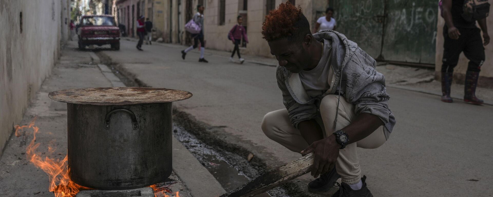 Um homem cozinha sopa sobre uma fogueira na calçada durante um apagão em Havana, Cuba. 4 de dezembro de 2024. - Sputnik Brasil, 1920, 05.12.2024