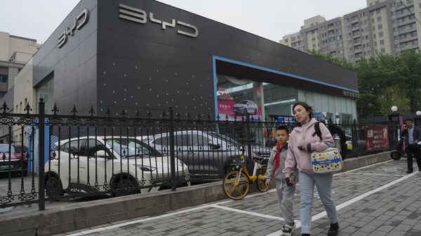 Moradores passam por um veículo elétrico Seagull da montadora chinesa BYD estacionado em um showroom em Pequim, 10 de abril de 2024 - Sputnik Brasil