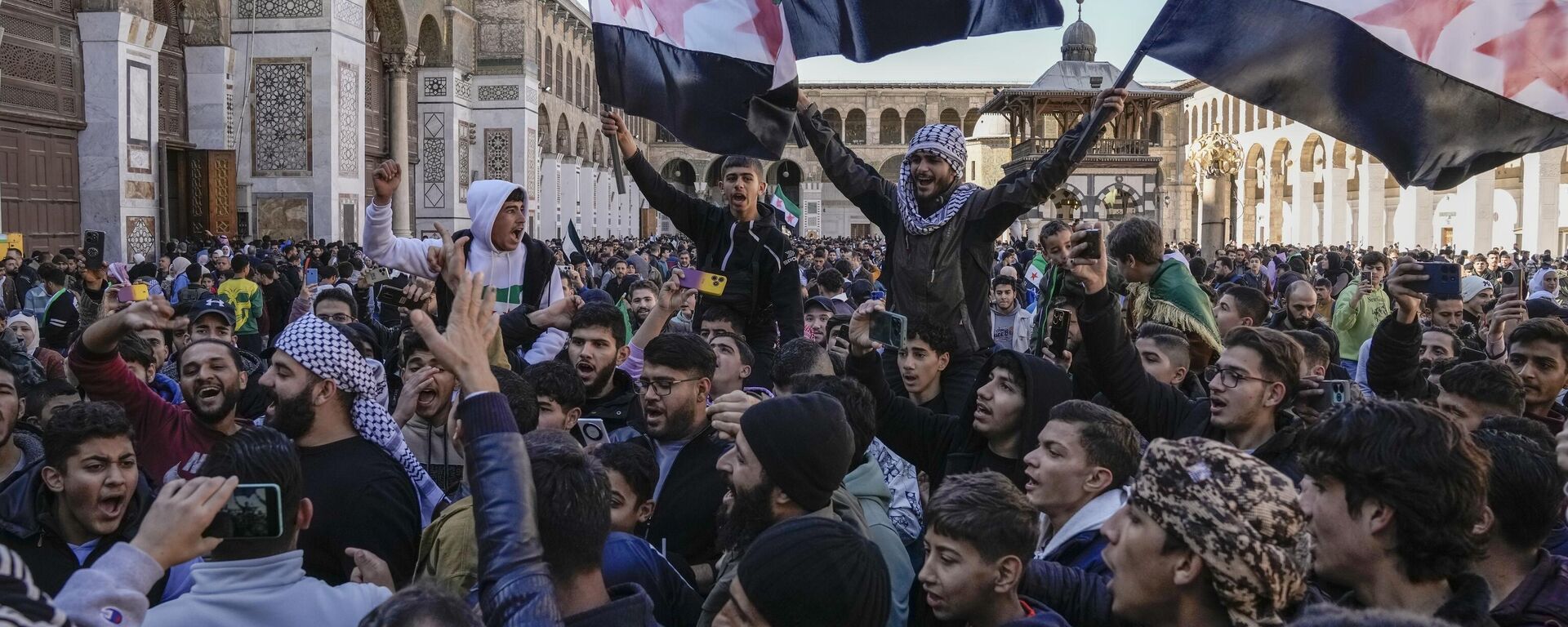 Manifestantes entoam slogans e agitam a nova bandeira síria enquanto se reúnem para as orações de sexta-feira na mesquita Omíada em Damasco. Síria, 13 de dezembro de 2024 - Sputnik Brasil, 1920, 26.12.2024