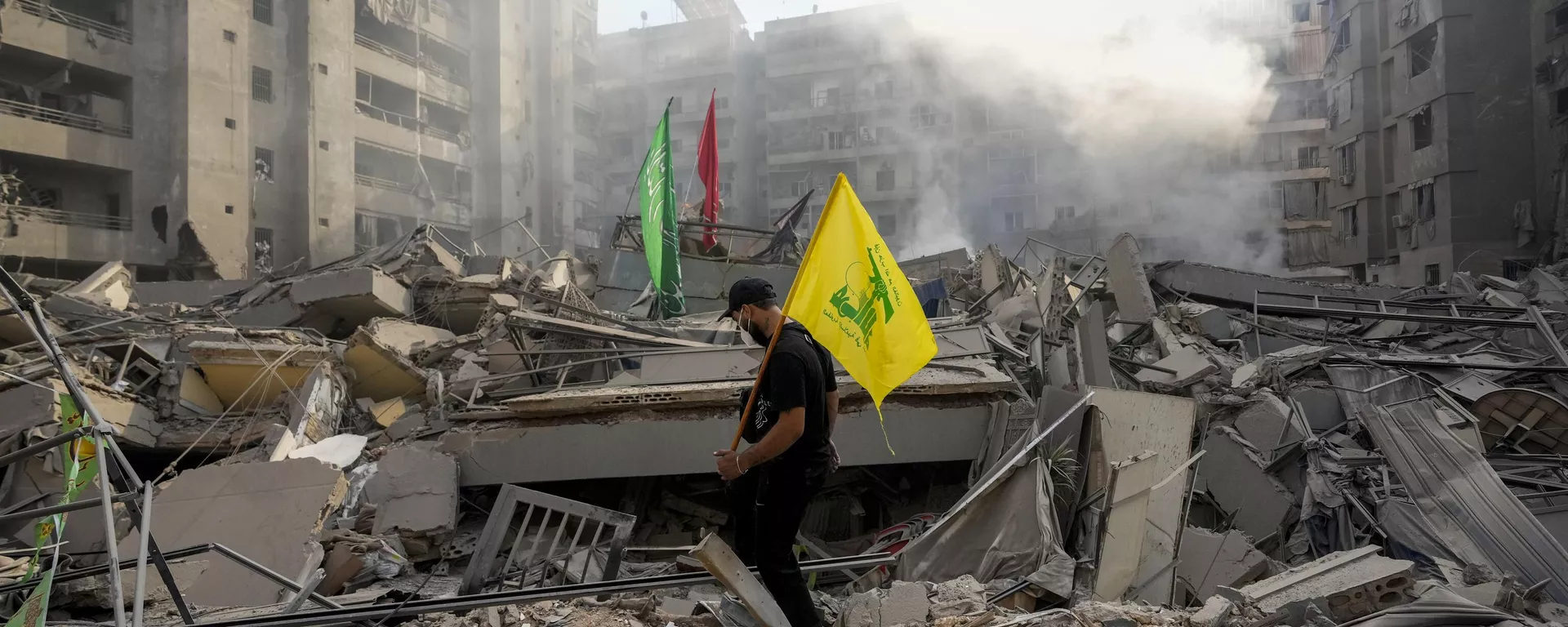 Um homem carrega uma bandeira do Hezbollah enquanto caminha sobre os escombros de seu apartamento destruído após um ataque aéreo israelense no Líbano, 1º de novembro de 2024. - Sputnik Brasil, 1920, 26.01.2025