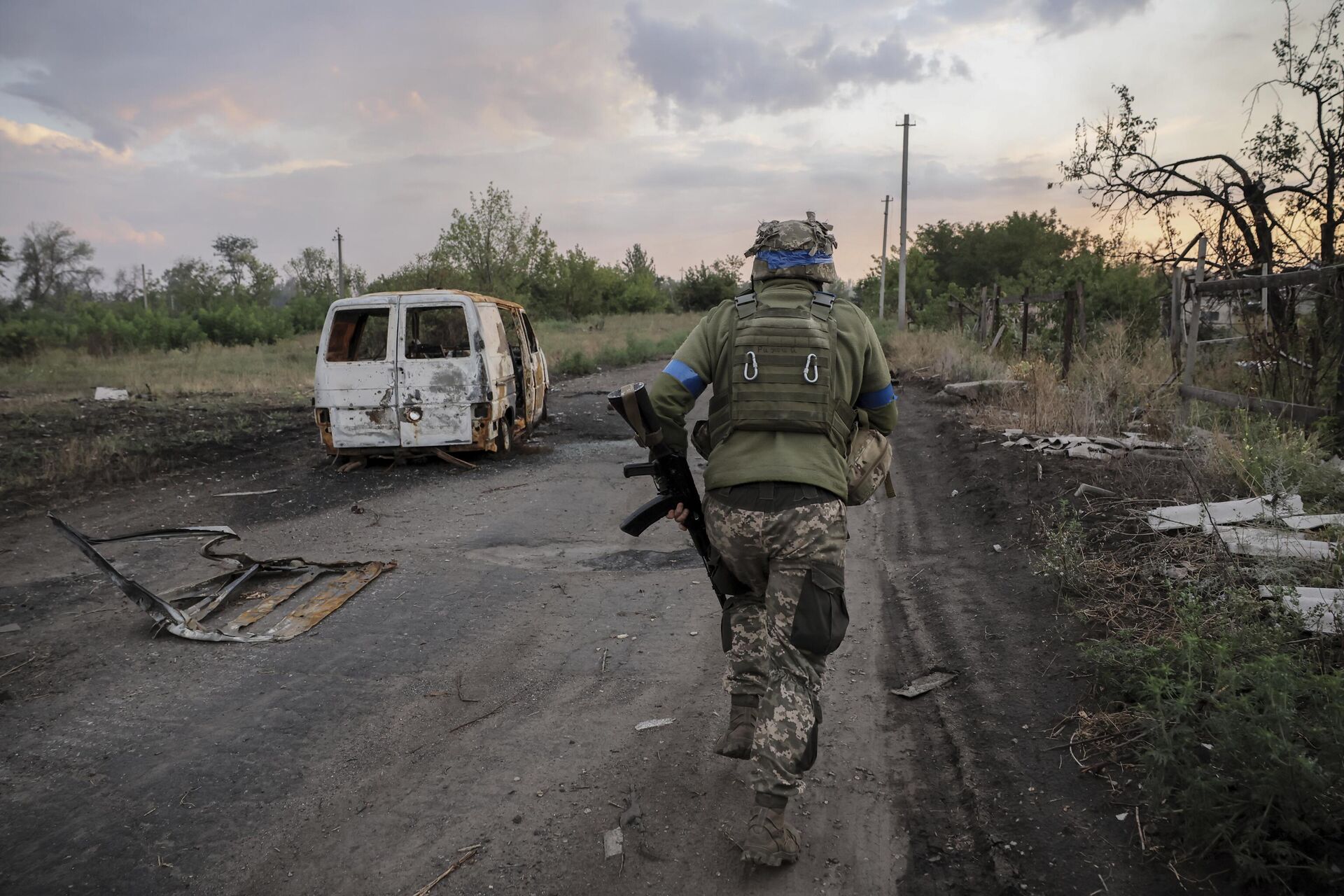 Um militar da 24ª Brigada Mecanizada da Ucrânia passa por um carro danificado na linha de frente na região de Donetsk, 6 de agosto de 2024