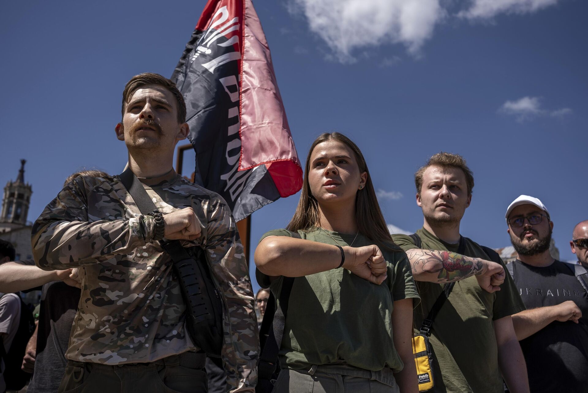 Pessoas realizam cerimônia fúnebre de combatente britânico em frente a uma bandeira do partido de ultranacionalista e neonazista ucraniano, Pravy Sektor (Setor Direito), em de julho de 2024