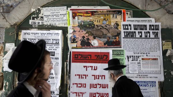 Judeus ultraortodoxos, ou haredi, passam em frente a um mural com publicações que condenam o recrutamento militar, no bairro de Mea Shearim, em Jerusalém, em 14 de julho de 2013 - Sputnik Brasil