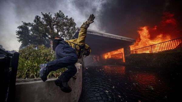 Um bombeiro pula uma cerca enquanto luta contra um incêndio em Los Angeles, EUA - Sputnik Brasil