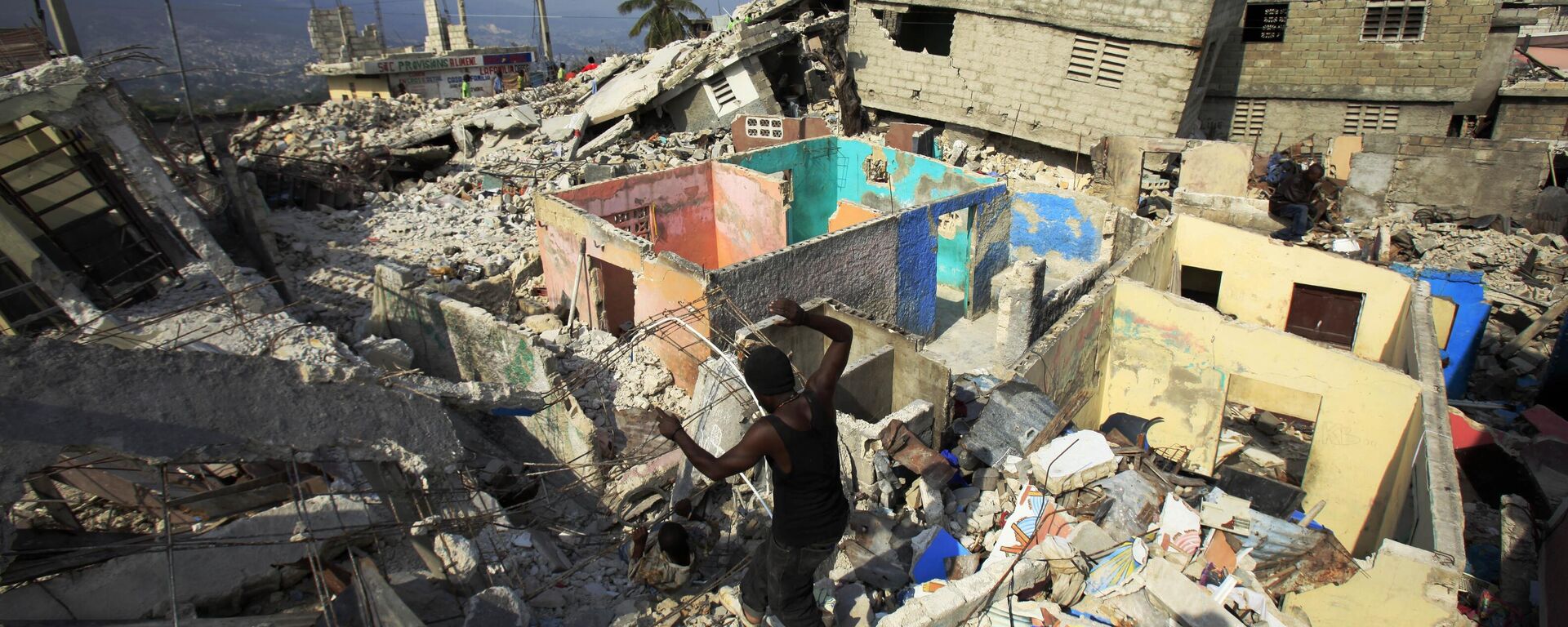 Um homem caminha entre os escombros de um prédio desabado em Porto Príncipe após o terremoto que atingiu o Haiti em janeiro de 2010. - Sputnik Brasil, 1920, 12.01.2025