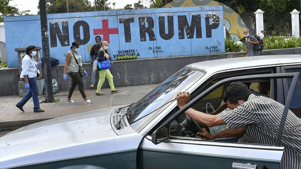 Um homem empurra seu carro que ficou sem gasolina enquanto pessoas usando máscaras de proteção como precaução contra a disseminação da COVID-19 passam por um mural com uma mensagem em espanhol: Chega de Trump em Caracas, Venezuela, 8 de novembro de 2020 - Sputnik Brasil