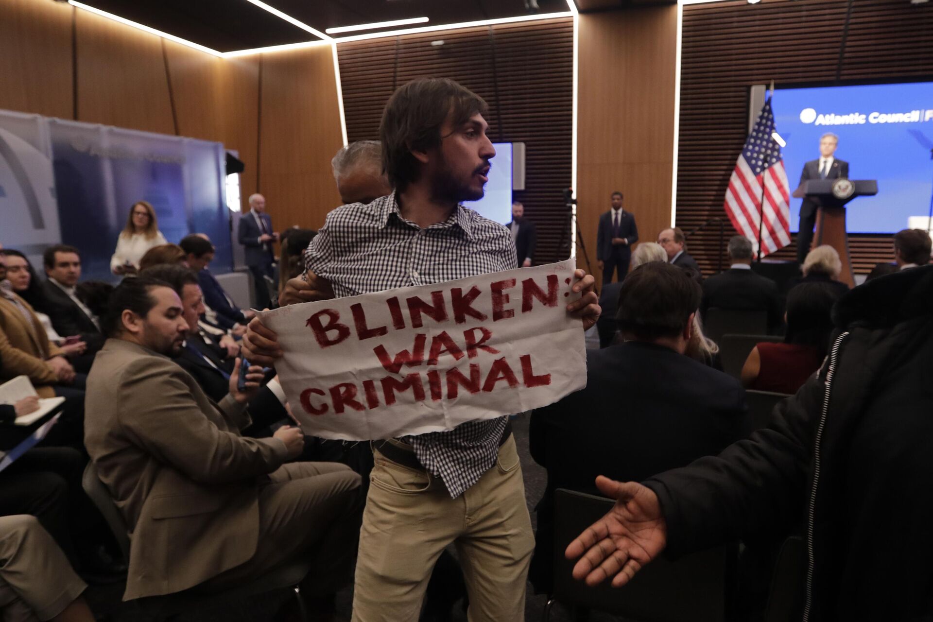 Um manifestante interrompe o secretário de Estado Antony Blinken durante um discurso no centro de análise Atlantic Council, 14 de janeiro de 2025, Washington.