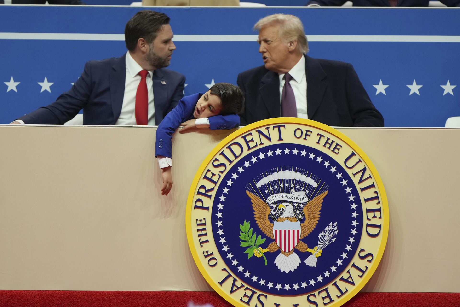 O vice-presidente dos EUA, J. D. Vance, à esquerda, o presidente Donald Trump, à direita, e o filho de Vance, Vivek, participam de um evento interno do desfile de posse presidencial em Washington, EUA, em 20 de janeiro de 2025