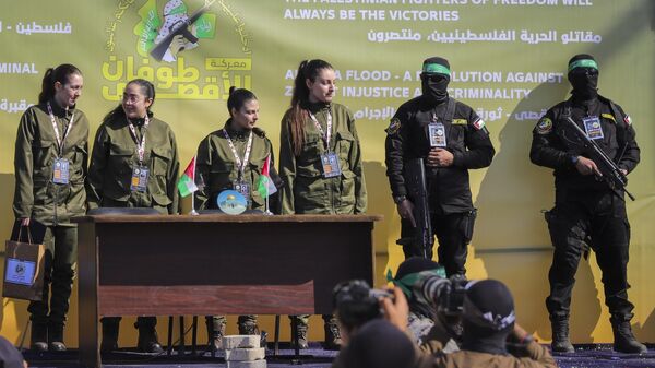 Soldado israelense faz reféns Naama Levy, Daniella Gilboa, Karina Ariev e Liri Albag, sem nenhuma ordem específica, em um palco em frente a uma multidão palestina antes de serem entregues à Cruz Vermelha na Cidade de Gaza, 25 de janeiro de 2025 - Sputnik Brasil