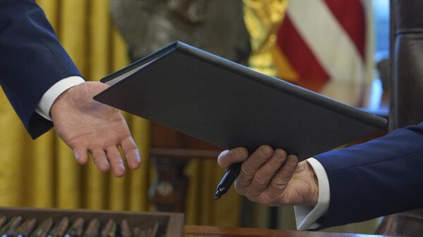 O presidente dos EUA, Donald Trump, entrega ordem executiva sobre Canadá e México ao secretário da equipe da Casa Branca, Will Scharf, no Salão Oval da Casa Branca, com a réplica da taça da Copa do Mundo ao fundo, em 4 de fevereiro de 2025, em Washington, EUA - Sputnik Brasil