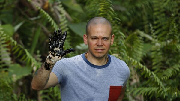 René Pérez, da banda porto-riquenha Calle 13, mostra sua mão coberta de óleo durante visita ao campo de petróleo de Aguarico, na região amazônica do Equador, em 2 de maio de 2014 - Sputnik Brasil