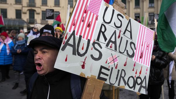 Um homem segura um cartaz com os dizeres: EUA: Fora da Europa: durante um protesto contra a Conferência de Segurança de Munique, em Munique, 15 de fevereiro de 2025 - Sputnik Brasil