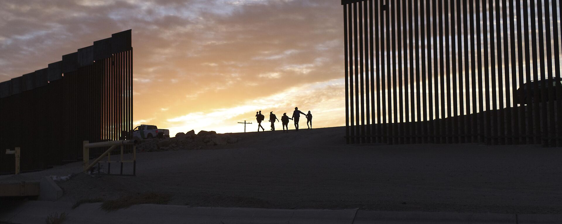 Duas famílias de migrantes do Brasil em busca de asilo passam por uma brecha no muro da fronteira para chegar aos Estados Unidos após cruzarem do México em Yuma, Arizona, 10 de junho de 2021 - Sputnik Brasil, 1920, 19.02.2025