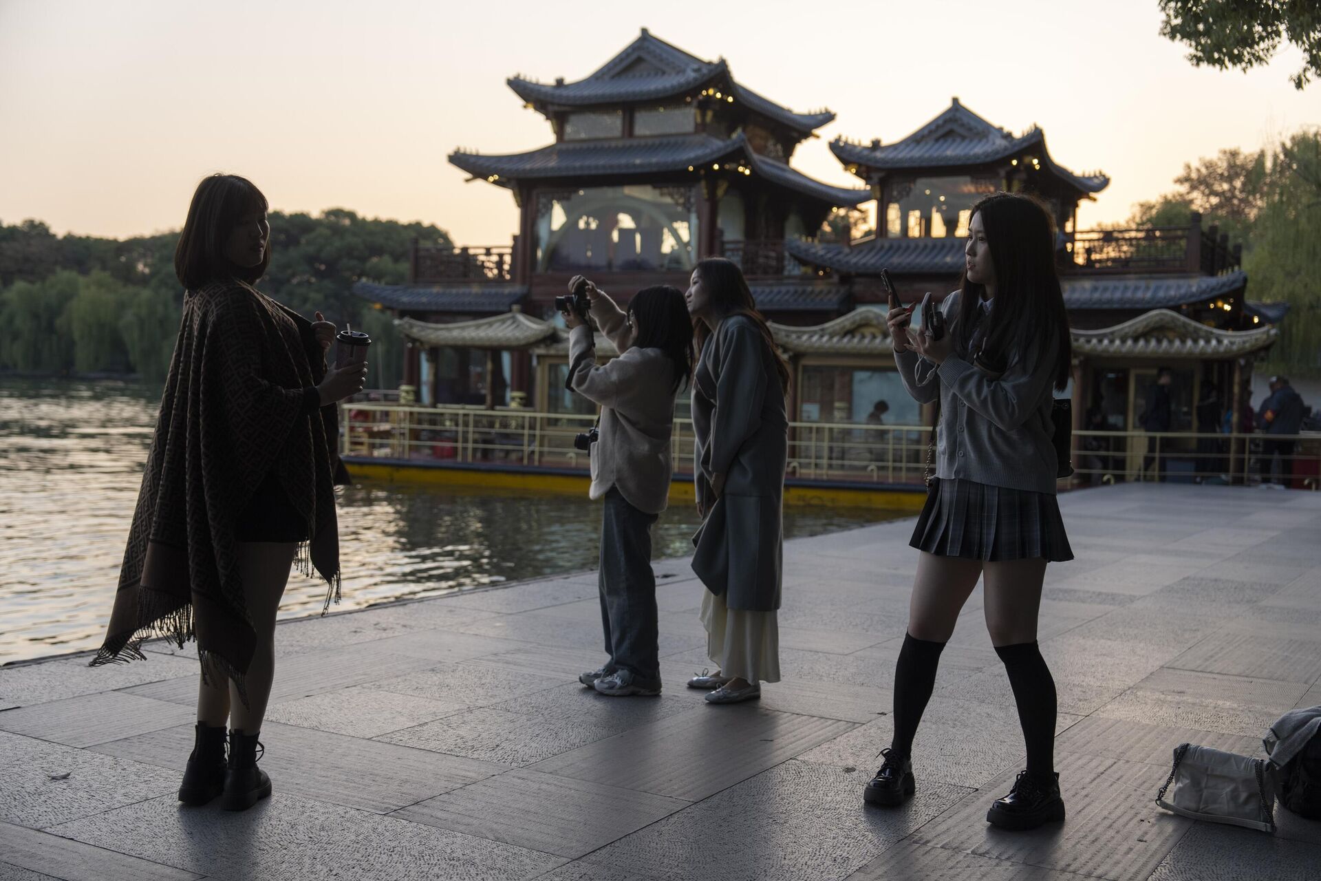 Visitantes tiram fotos ao longo do cênico Lago Oeste durante o crepúsculo em Hangzhou, cidade-sede da empresa chinesa de inteligência artificial DeepSeek, na província de Zhejiang, 2 de dezembro de 2024 - Sputnik Brasil, 1920, 21.02.2025